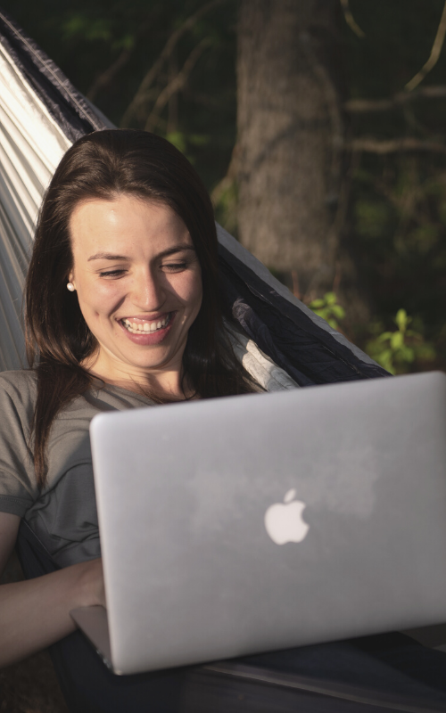 Ana McRae, Life and Business Coach, using laptop on hammock