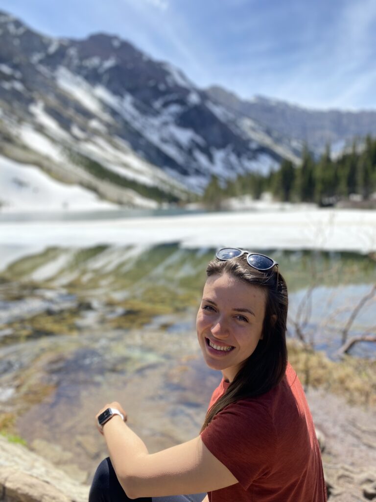 executive business coaching with ana mcrae sitting in front of lake with mountains